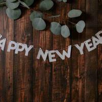 A sign says Happy New Year, over a wooden table, with eucalyptus leaves.