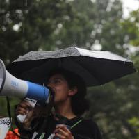 Women standing under umbrella and speaking into a megaphone