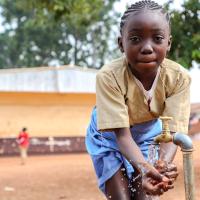 Un jeune fille qui lave ses mains dans la cour de l'école